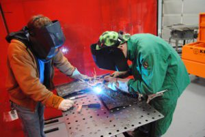 Career academy teacher assisting student with welding